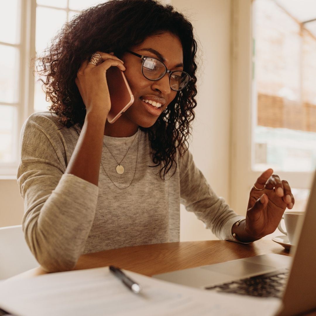 woman on phone call while using laptop